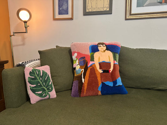 Decorative pillows on a green sofa with a wall lamp and framed pictures in the background.