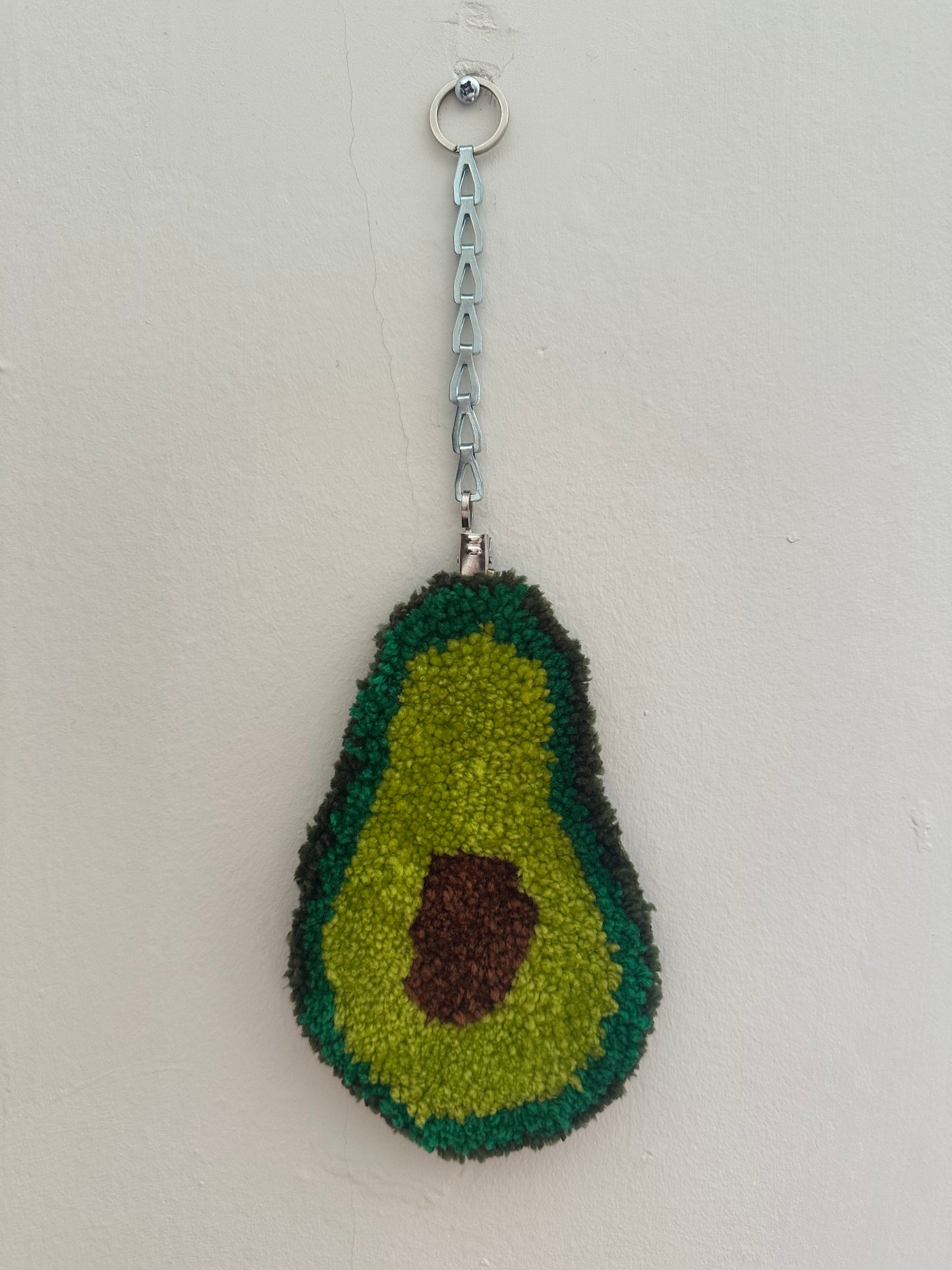 Avocado-shaped rug with a chain on a light gray background