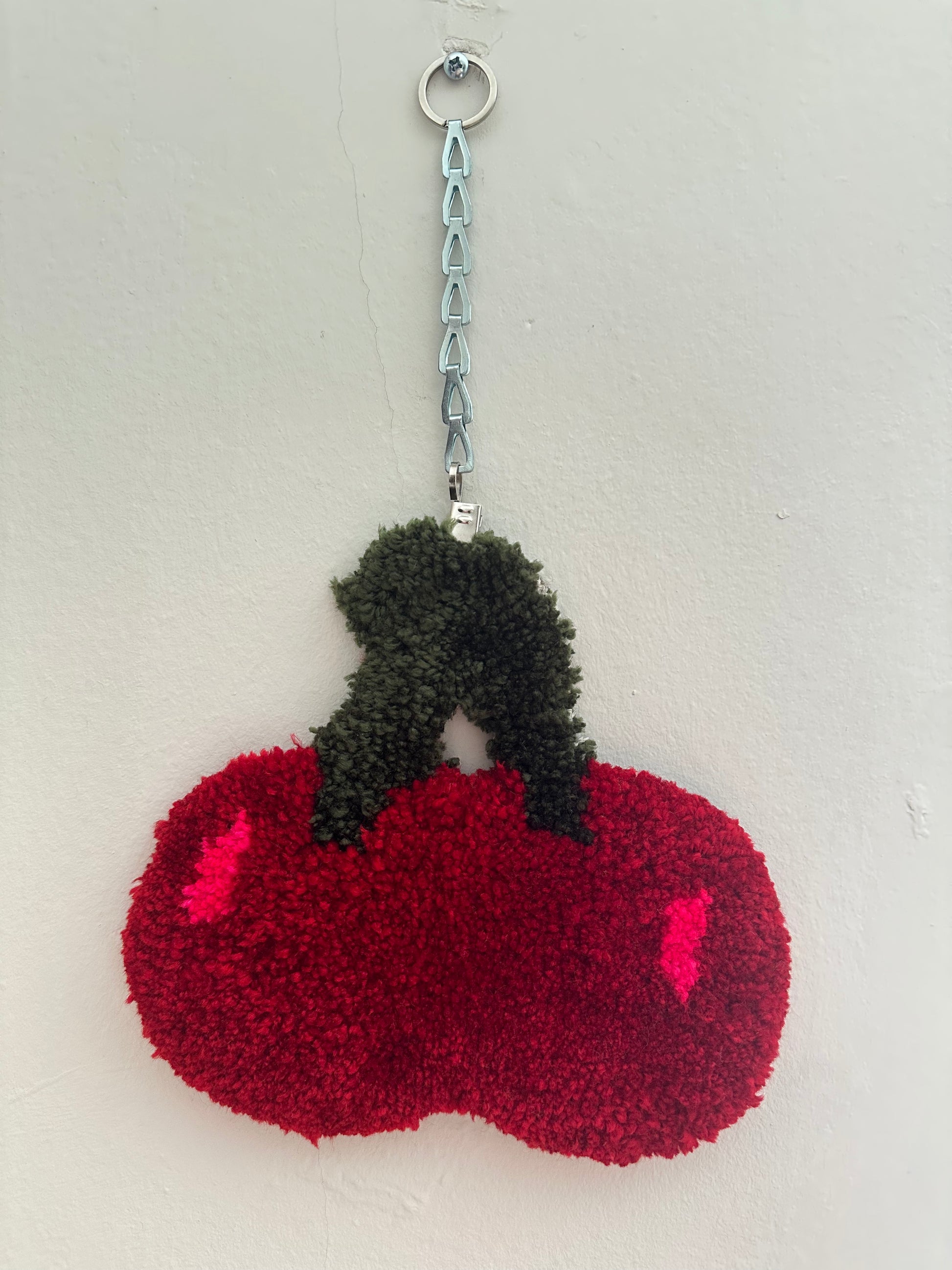 cherry rug hung on a white wall with a chain