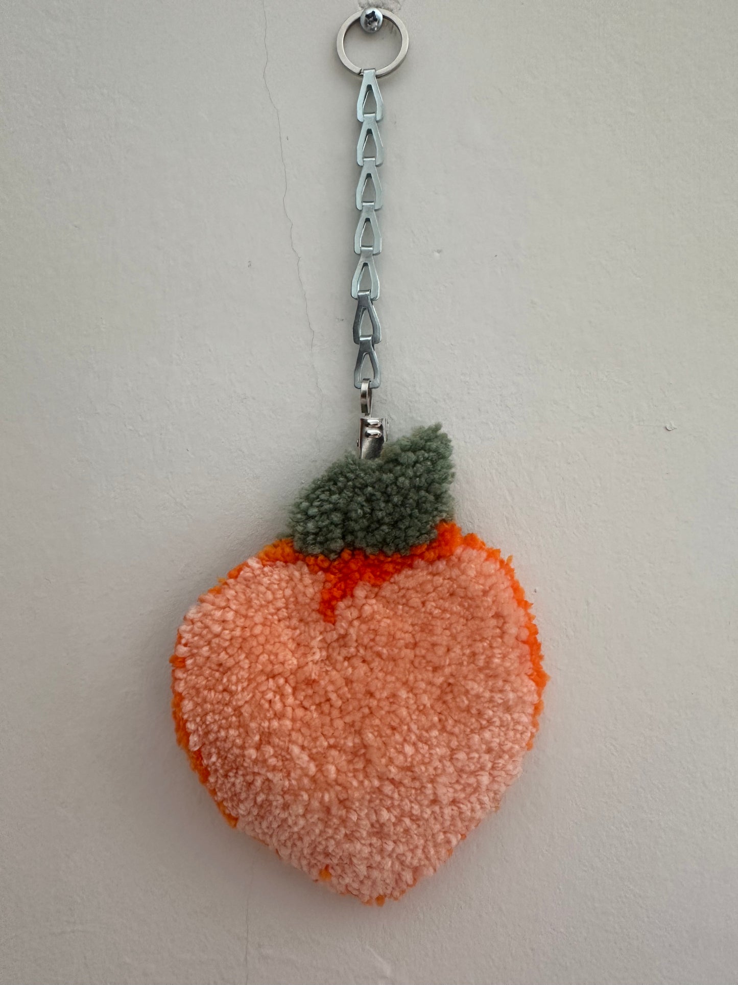 Mini peach rug hung on the wall with a chain